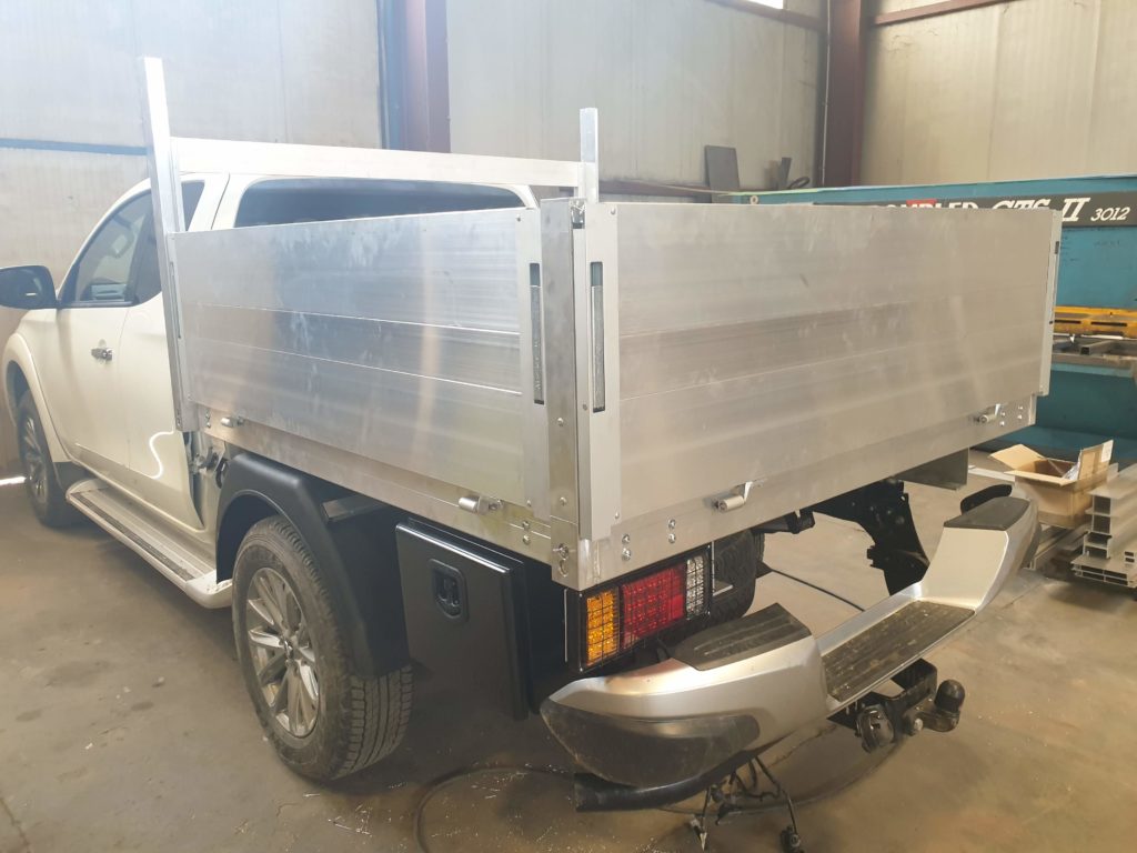 Pick-up équipé d’une benne en aluminium à ridelles hautes — vue arrière de trois quarts.