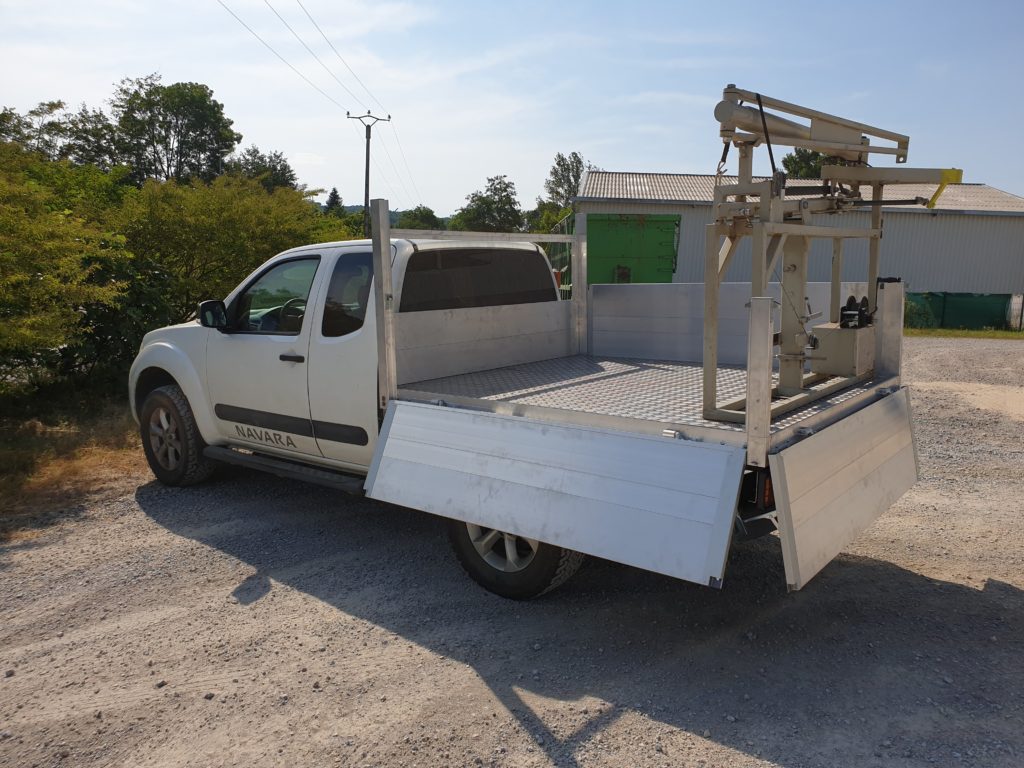 Pick-up avec benne en aluminium, ridelle ouverte et support à l’arrière du plateau.