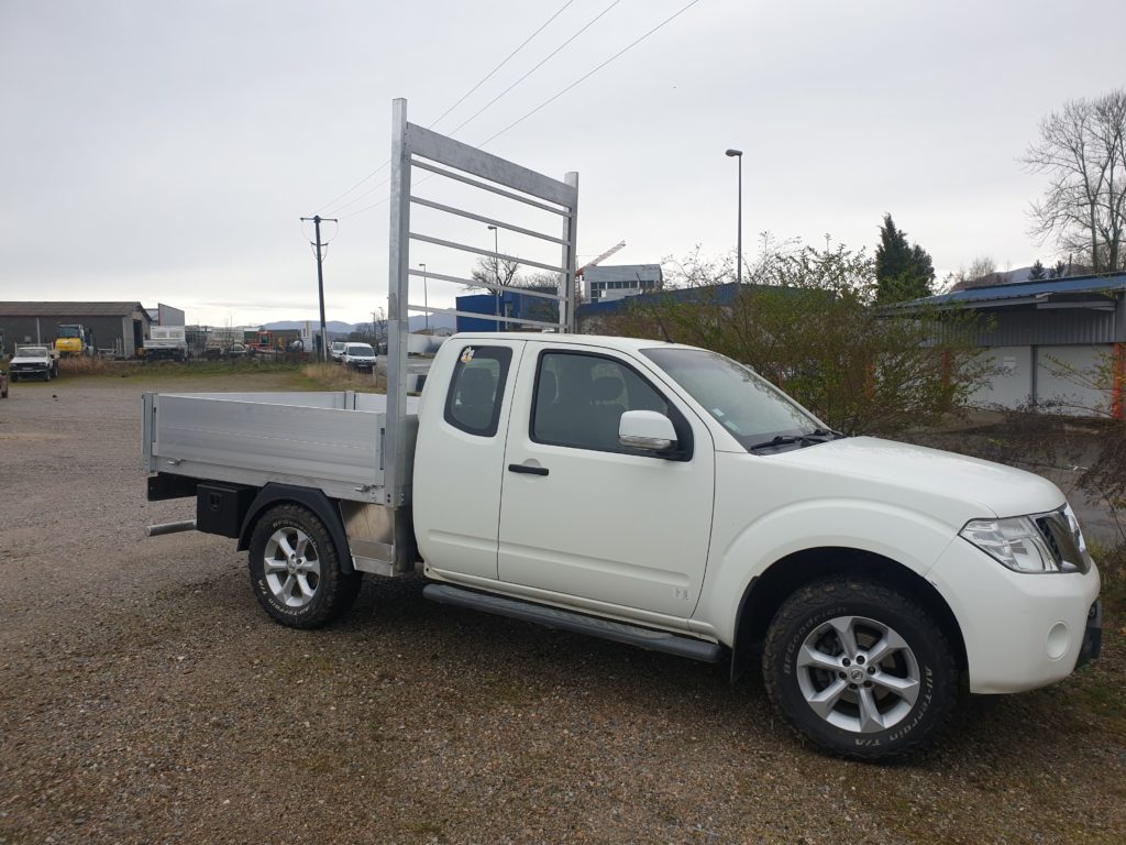 Pick-up avec benne en aluminium et porte-échelle derrière la cabine.