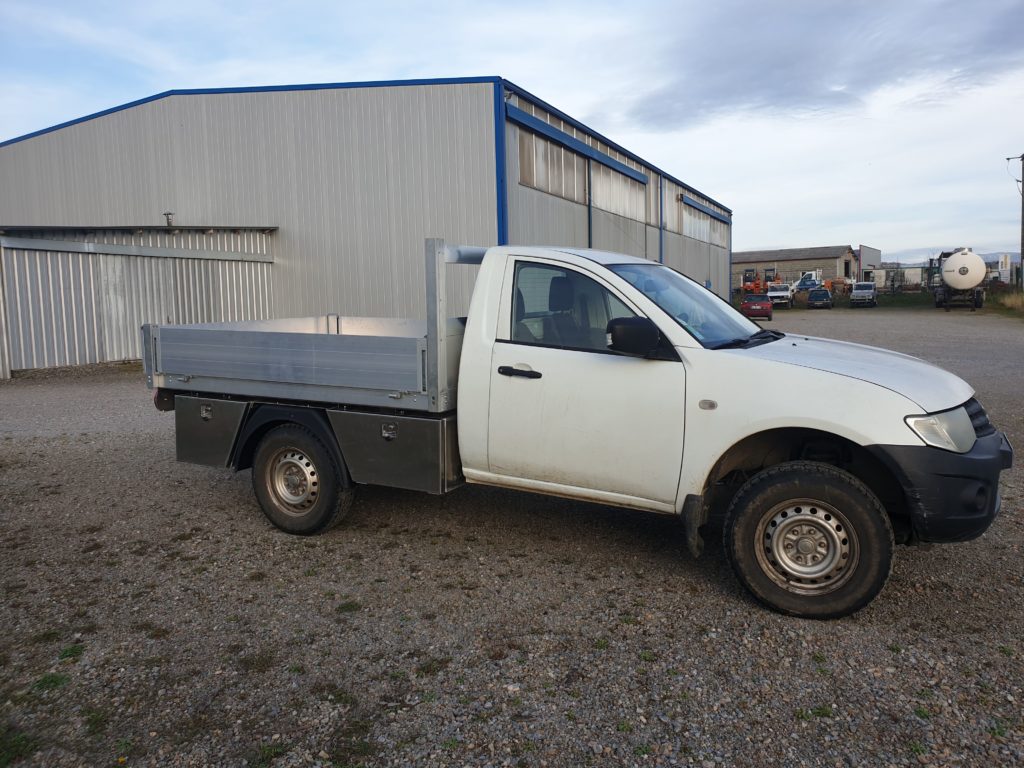 Pick-up équipé d’une benne en aluminium à ridelles basses — vue d’ensemble en extérieur.