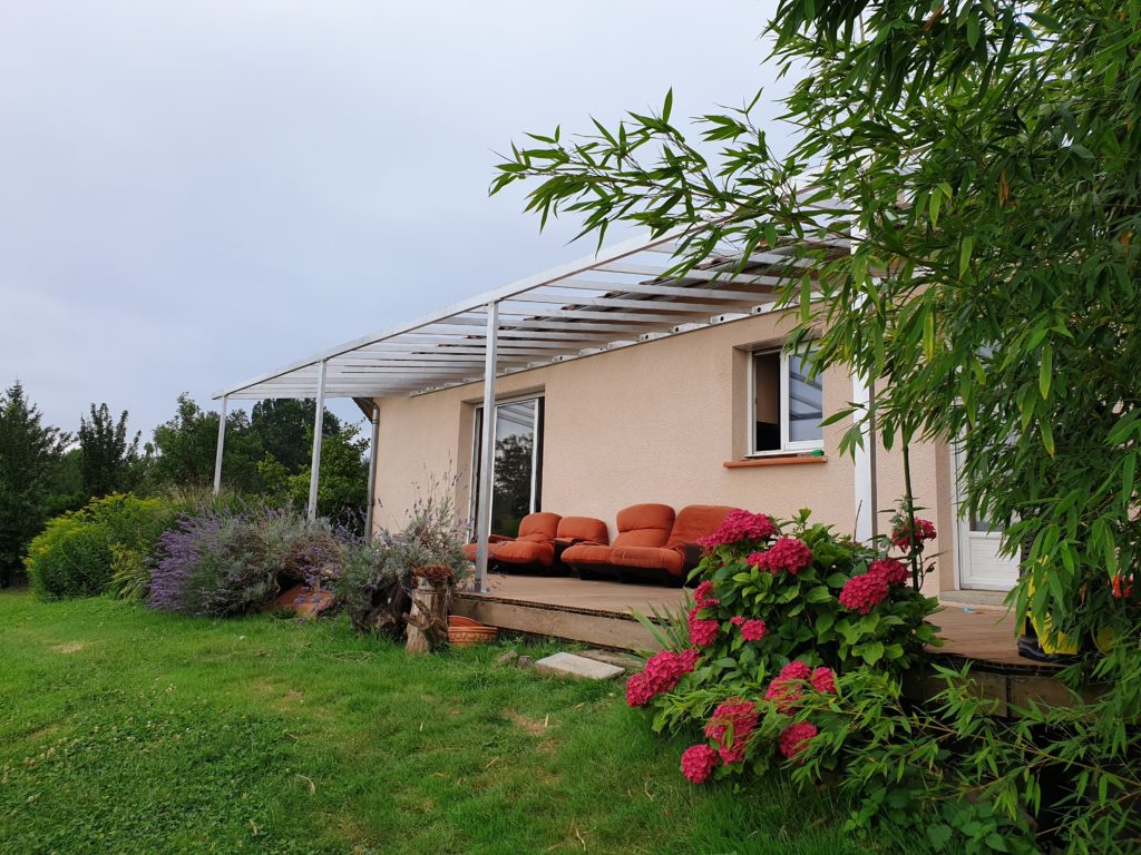Pergola métallique adossée à une maison — vue d’ensemble.