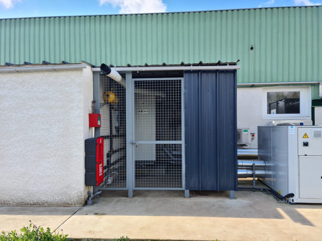 Accès d’un bâtiment industriel — porte et protection métallique.