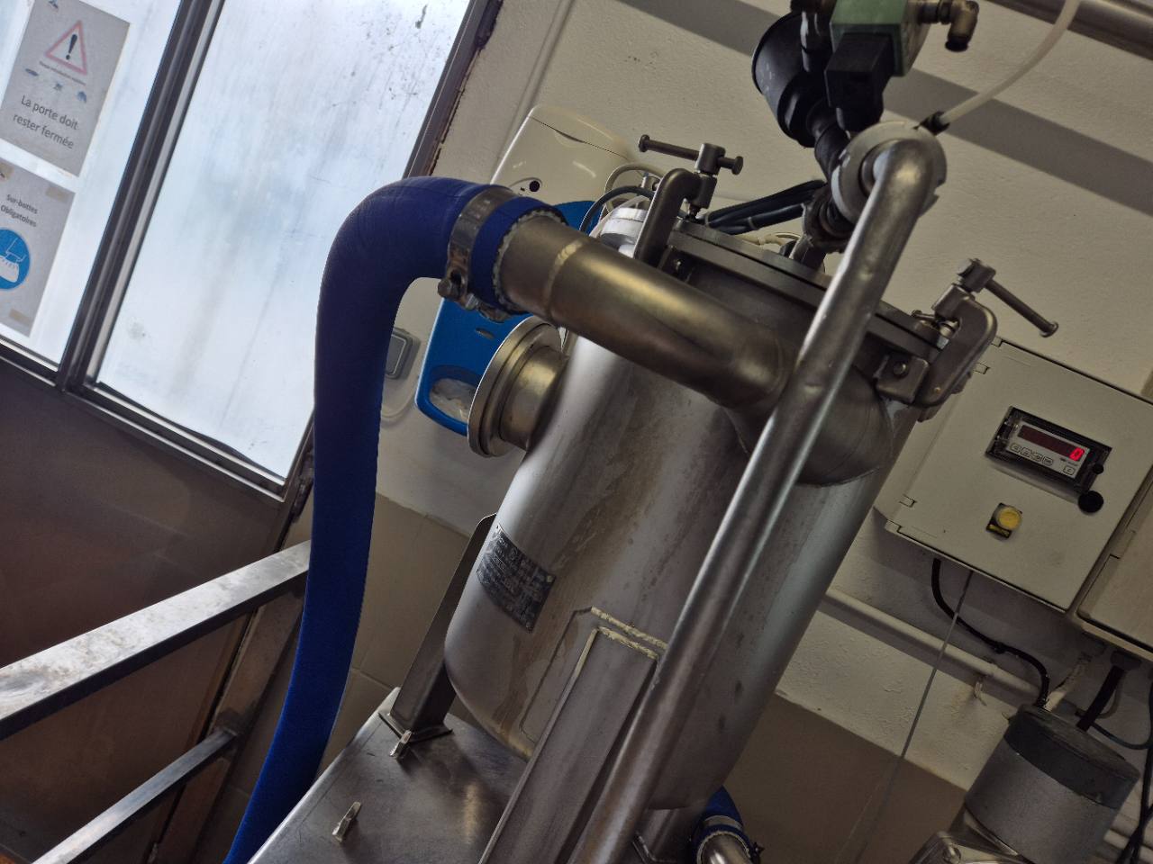 Équipement industriel métallique avec raccordements et support.