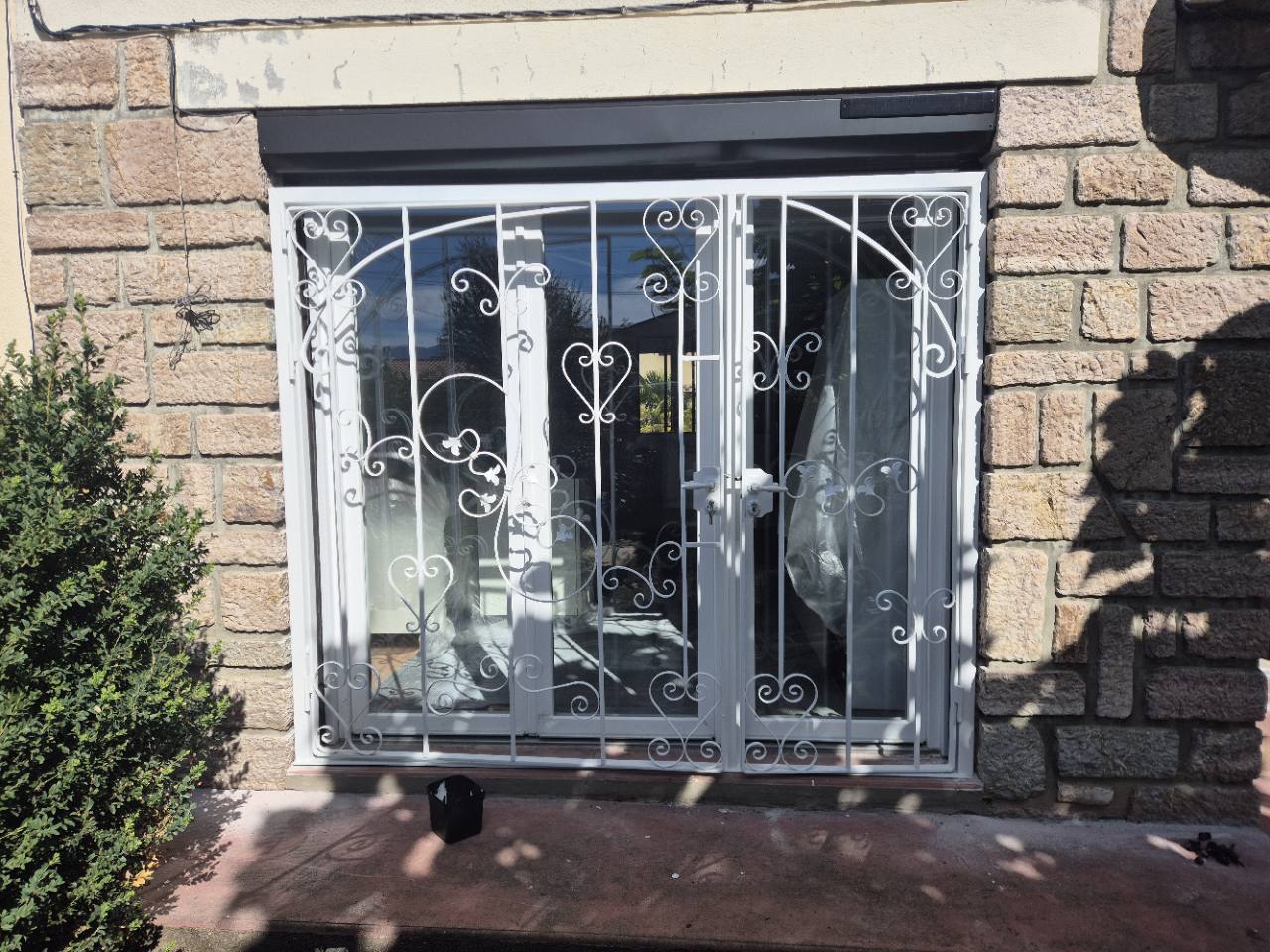 Grille métallique décorative blanche posée devant une porte-fenêtre.