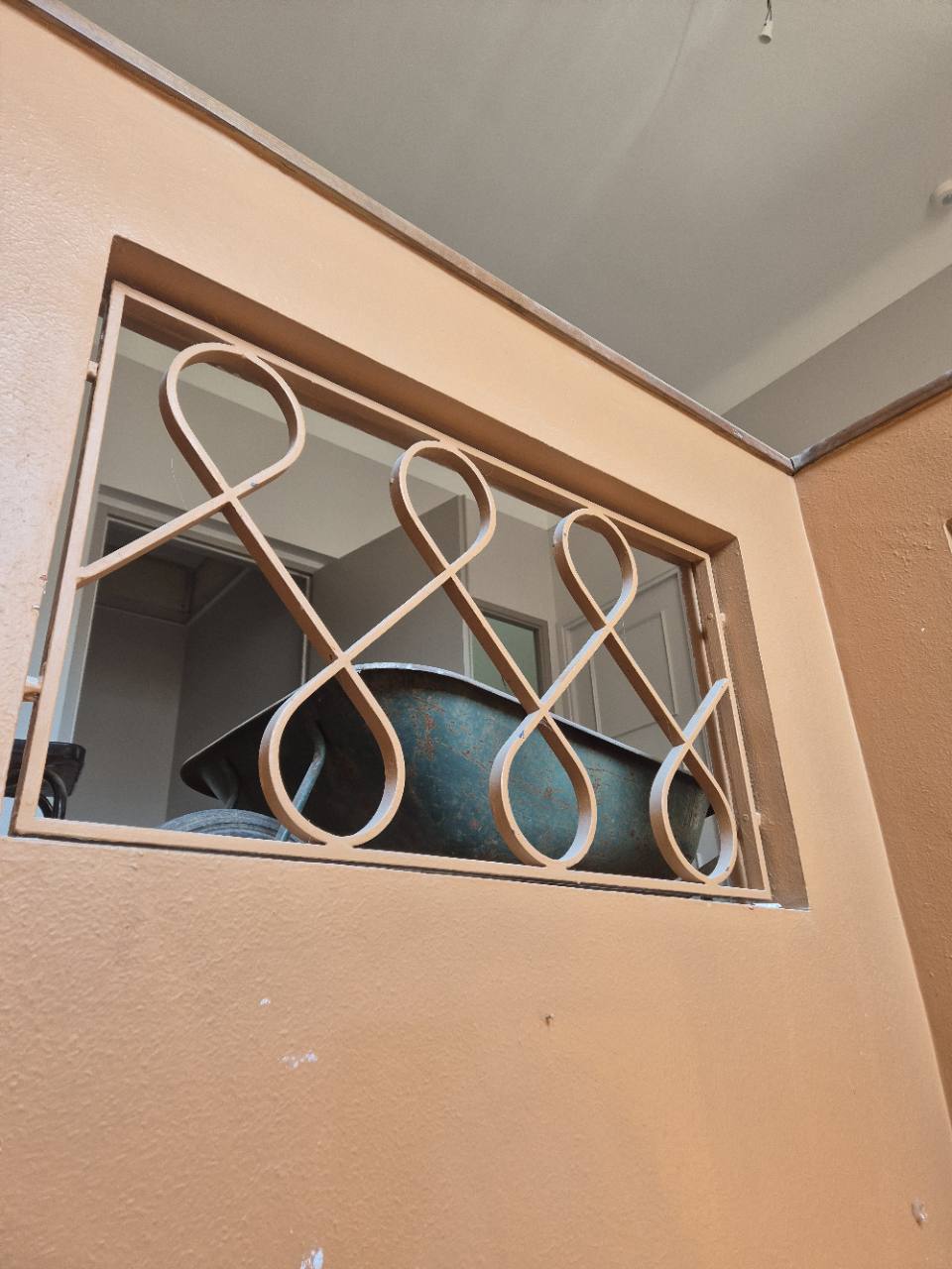 Grille métallique décorative à motifs courbes, posée devant une fenêtre.
