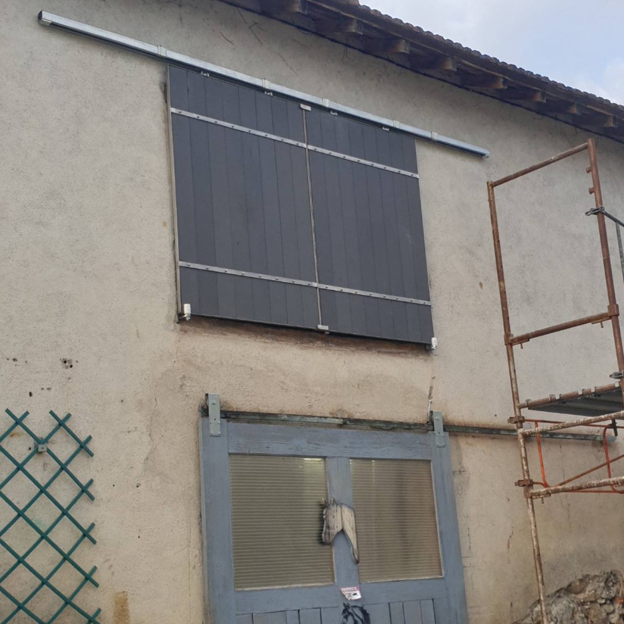 Panneaux coulissants extérieurs équipés d’un rail et de ferrures métalliques.