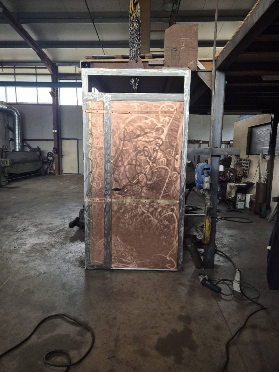 Vue d’ensemble de la porte métallique avec habillage en cuivre, présentée à l’atelier.