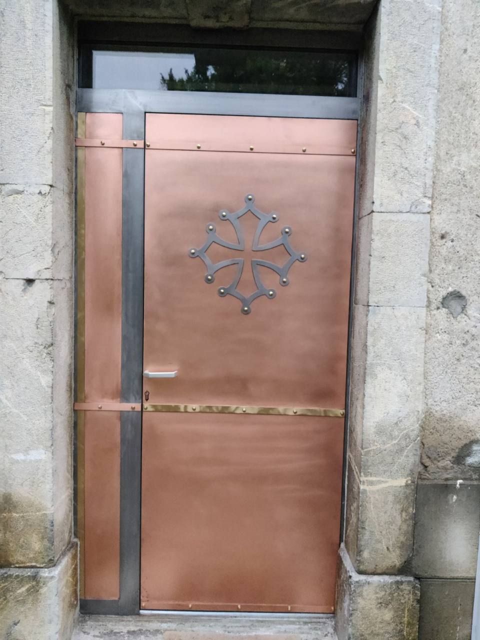 Porte métallique décorative avec motif de croix occitane.